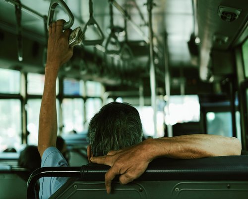 Man waiting for public transport in the city, holding a briefcase