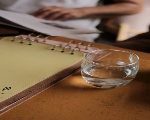 Notepad, pen, and a glass of water on a modern desk preparing for an online meeting